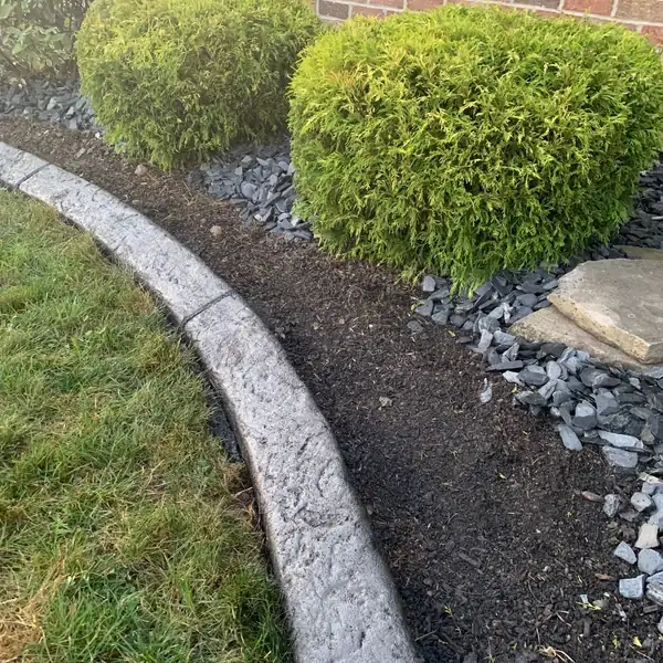 Concrete curb along a rock bed and shrubs beside a house