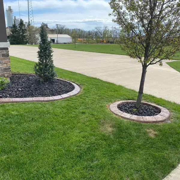 Curved concrete curbing around mulch beds along a driveway