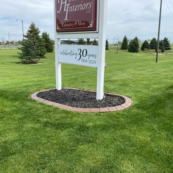 Concrete curb mulch bed around a sign in a lawn