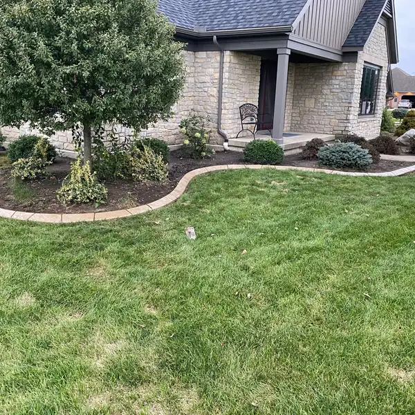 Curving concrete curb around landscaped beds in front of a home