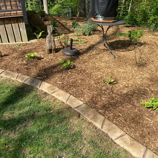 Curved concrete curb along a mulch bed with new plants