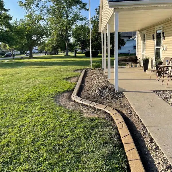 Concrete curb along a walkway beside a house with a covered porch
